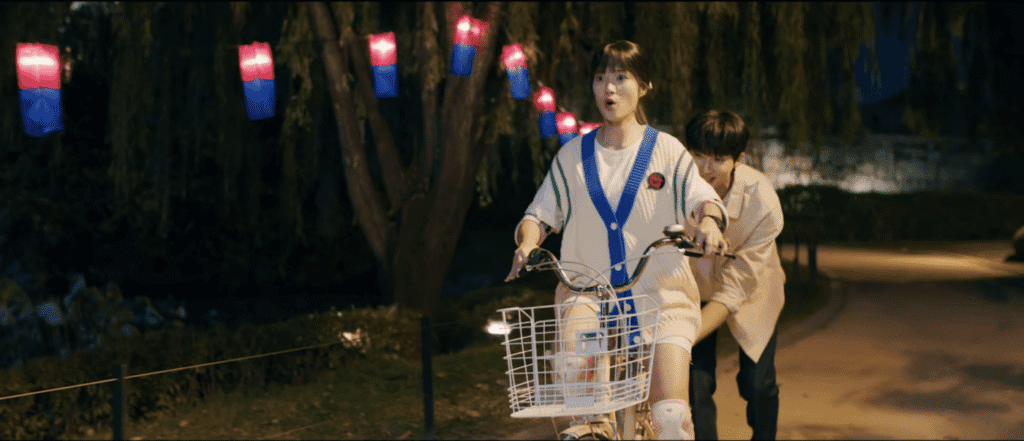 K-drama couple on bicycle at Banghwasuryujeong with colorful lanterns